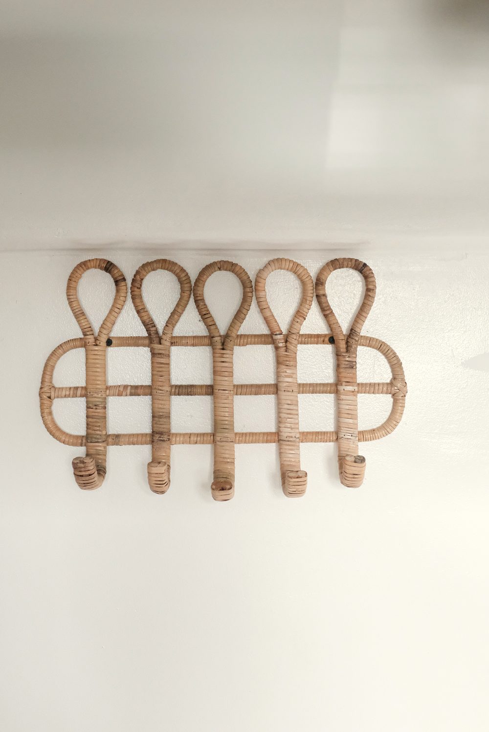 Woven rattan hook rack on a white wall beside a bunk.